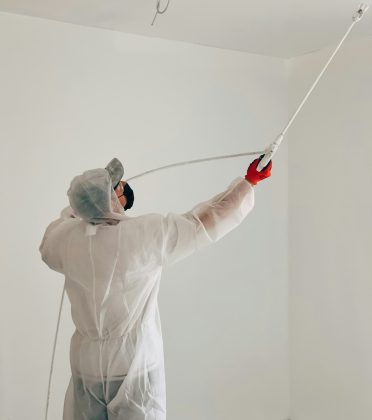 Man paints ceiling with a paint sprayer